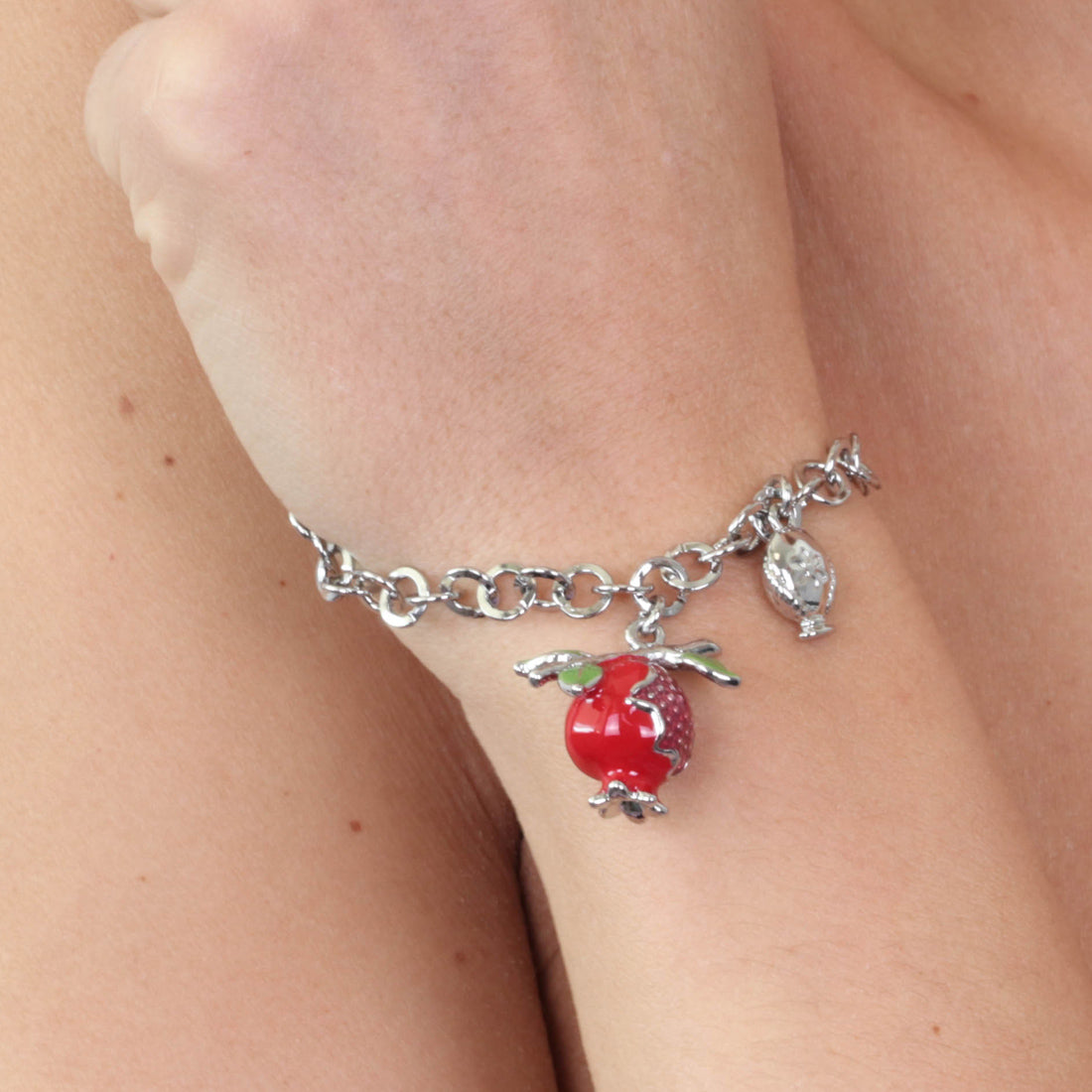 Metal bracelet with pendant pomegranate embellished with colored enamels and small pump on the side