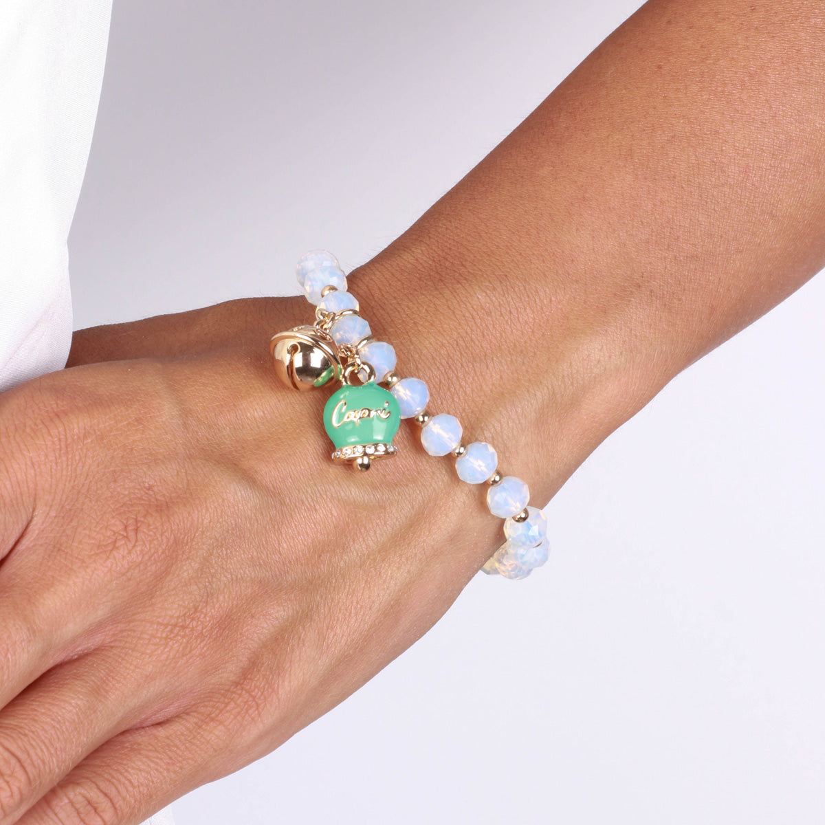 Metal bracelet with green bell and small rattle with white stones