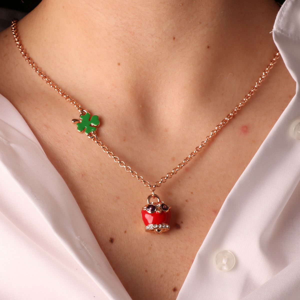 Metal necklace with four -leaf clover and owl charming bell with red nail polish and white crystals