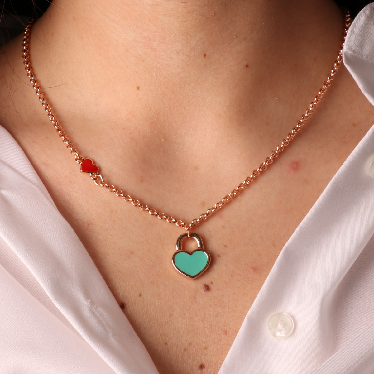 Metal necklace with red heart and heart padlock with turquoise nail polish