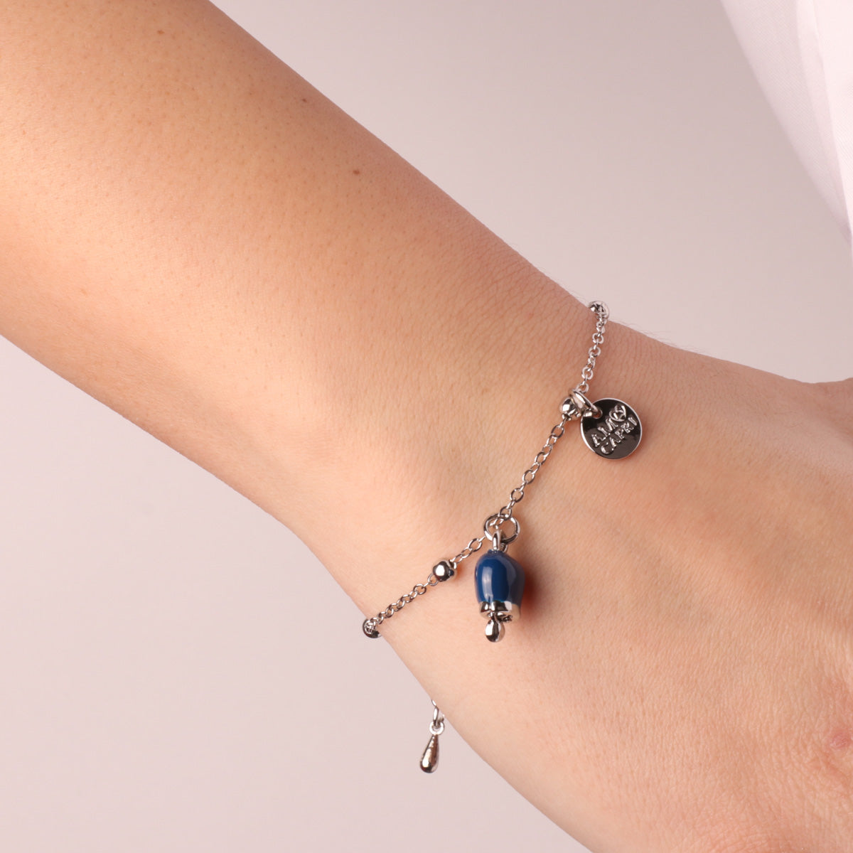Metal bracelet with pendant charm bell, embellished with blue enamel and light point